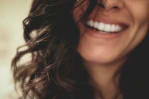 Close-up on a person smiling, while their long hair covers part of their face.