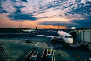 An airplane resting at a boarding station during a sunset.