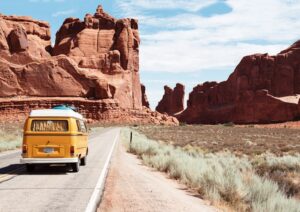 Wide shot of a yellow van on a road in-between canyons.