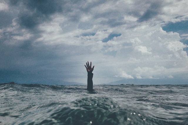 A hand reaching out from below waves.