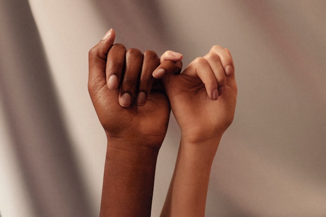 Close-up on two hands with their pinky fingers interlocked.