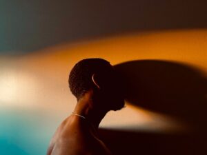 Close-up on a person in shadow being cast in orange and blue light.