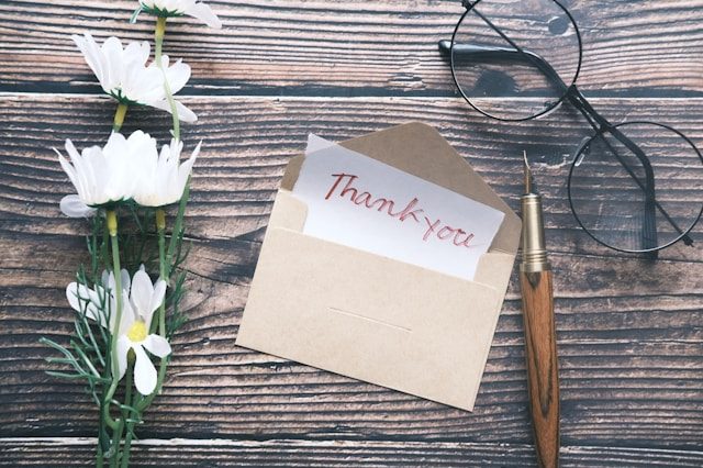 A beige envelope opened to a thank you note.